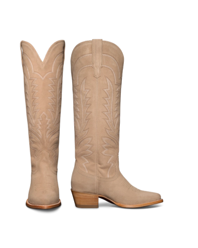 A pair of tall, tan cowboy boots with intricate stitching and wooden heels, displayed against a black background.