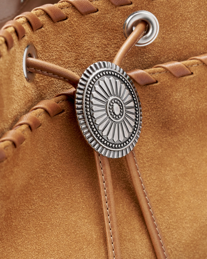 Close-up of a brown leather bag with intricate stitching and a silver button featuring a decorative circular design.