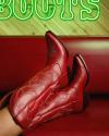 Person wearing red cowboy boots reclines on a red couch; a neon green sign reading "BOOTS" is partially visible in the background.