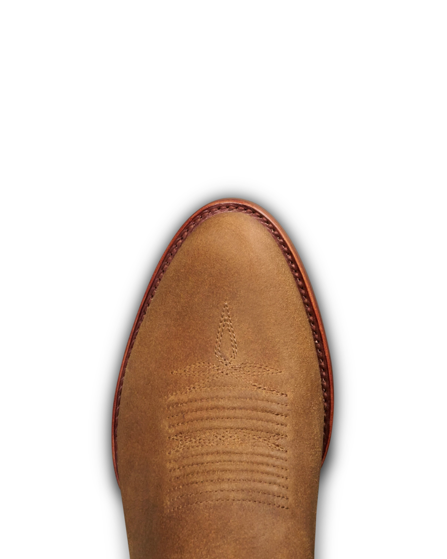 The Buck in Copper Cowhide. Close-up view of the toe of a brown leather cowboy boot with stitched decorative patterns and a reddish-brown welt, crafted from Copper Cowhide.