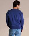 Back view of man wearing the cobalt blue sweatshirt in a photo studio