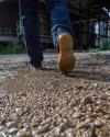 Pair of boots with rubber sole walking through water puddle