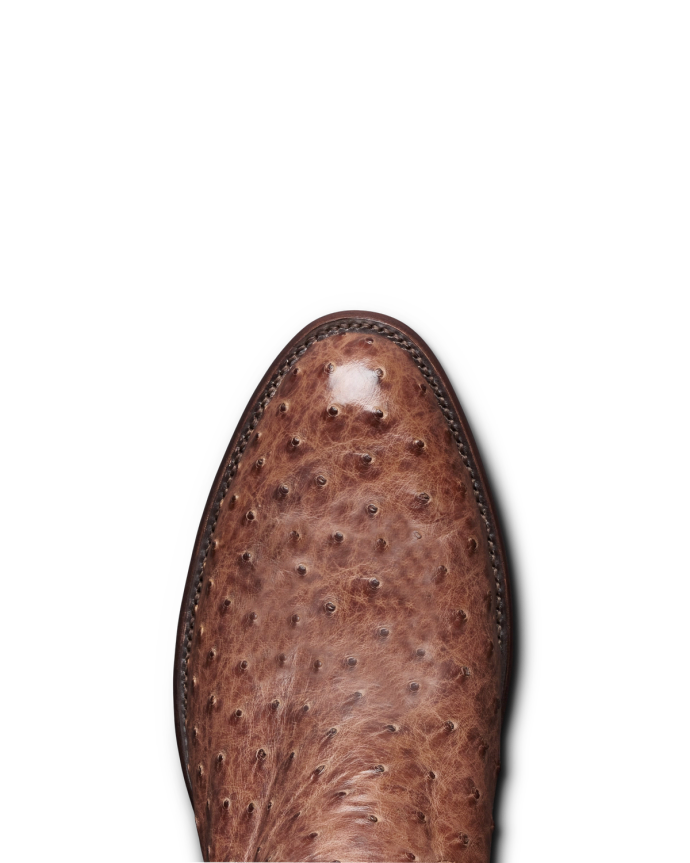 Close-up of the toe of a brown leather shoe with a textured, dot-patterned finish, situated against a black background.