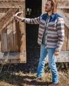 Man wearing the wildcat overshirt on a ranch opening a barn door.