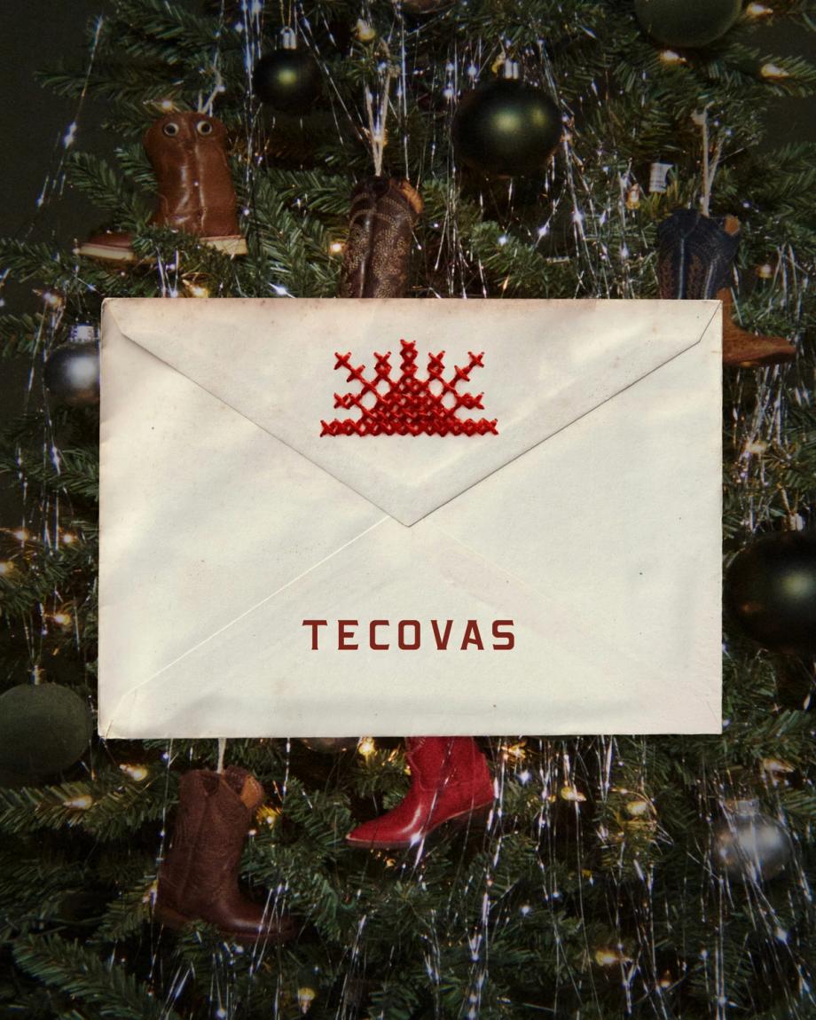 An envelope with the Tecovas logo centered on a Christmas tree decorated with miniature cowboy boot ornaments.