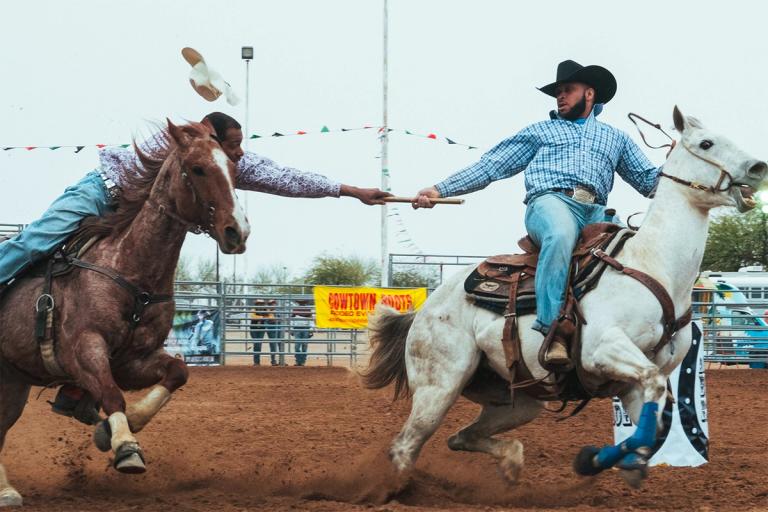 cowboys passing the baton on horses