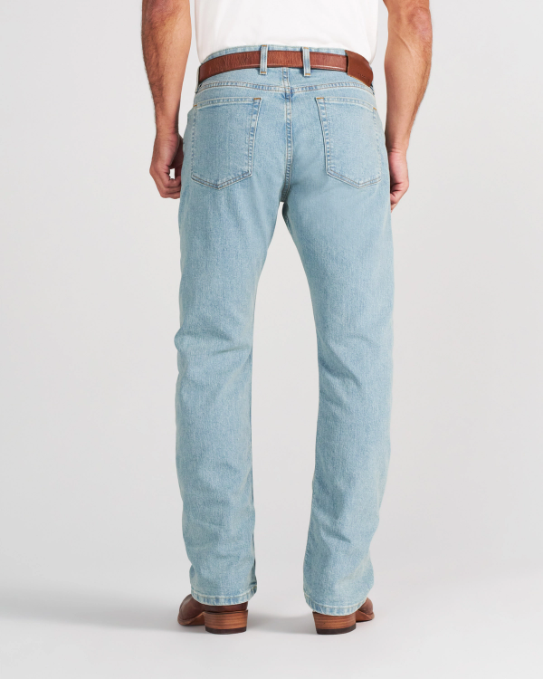 A person seen from behind wearing light-wash blue jeans, a white shirt, a brown leather belt, and brown boots.