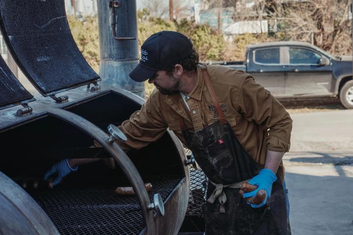 man placing meats into a smoker