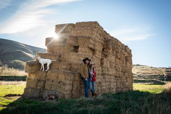 couple standing by a wall of hay bails