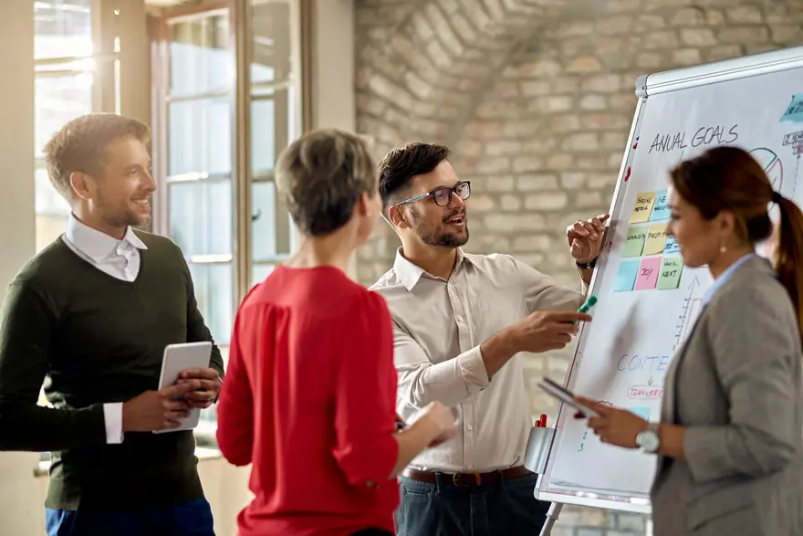 Small team collaborating on a pitch presentation at a whiteboard