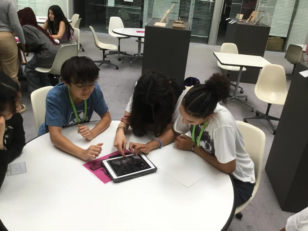 Student sitting round table looking at information on an iPad.