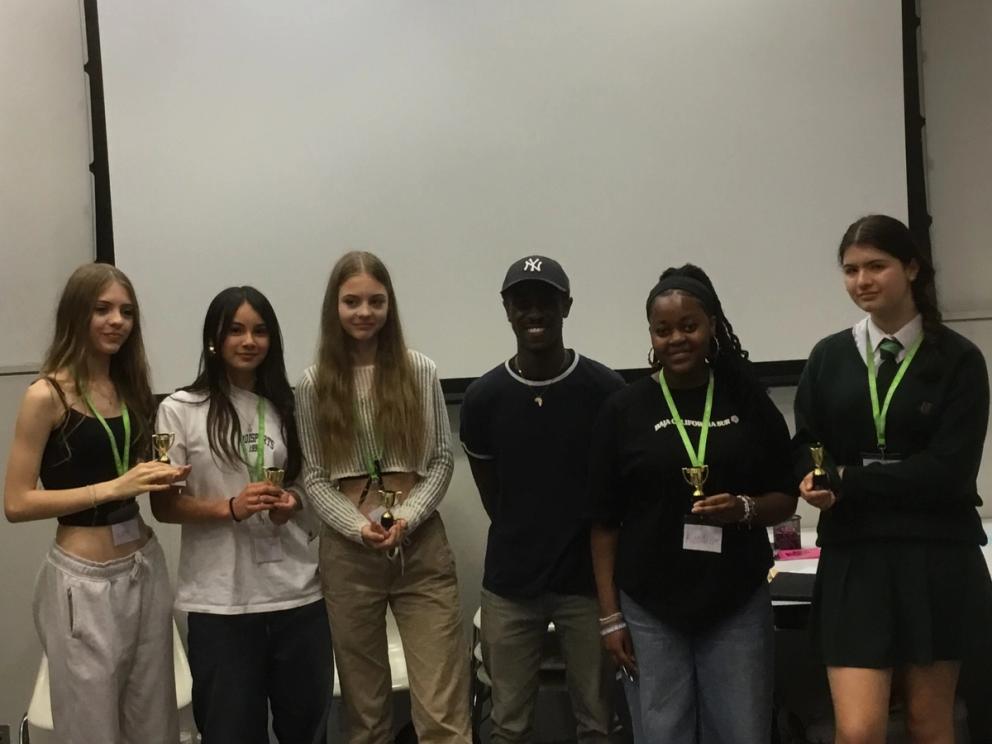 Students standing and holding small trophies