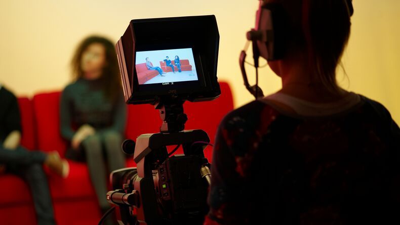 Student filming others sitting on a sofa