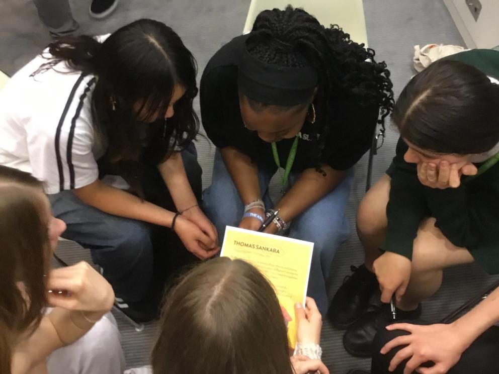 Students sitting in a circle. Leaning forwards. Collaborating to write their rap.