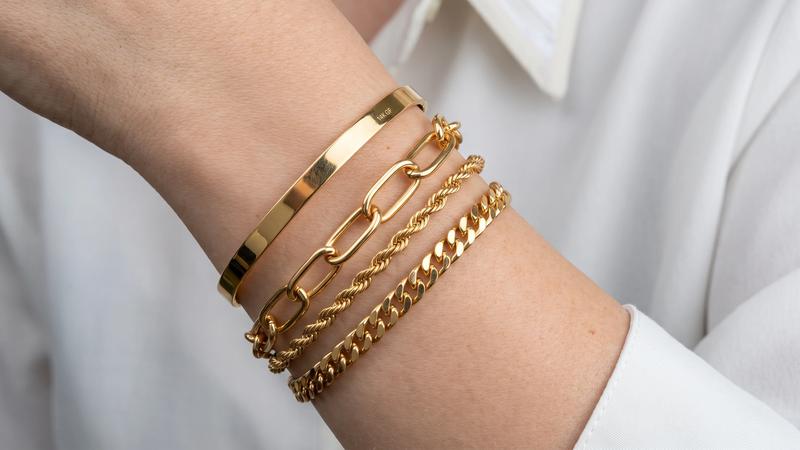 Stacked gold-plated bracelets with different chain styles