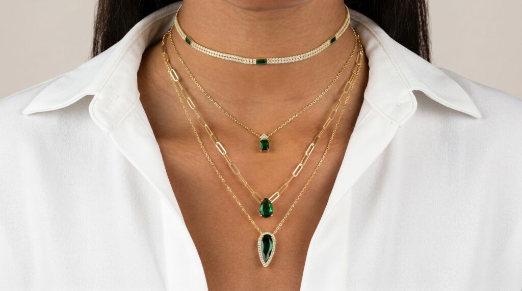 Jewelry featuring gemstones like emeralds, crafted into pendants and necklaces.