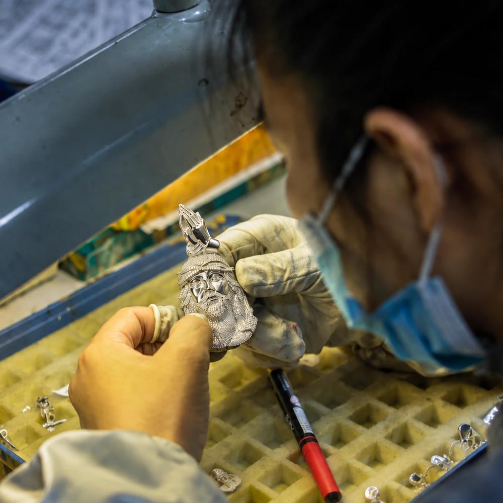 Jewelry worker inspecting a custom hip hop pendant during production