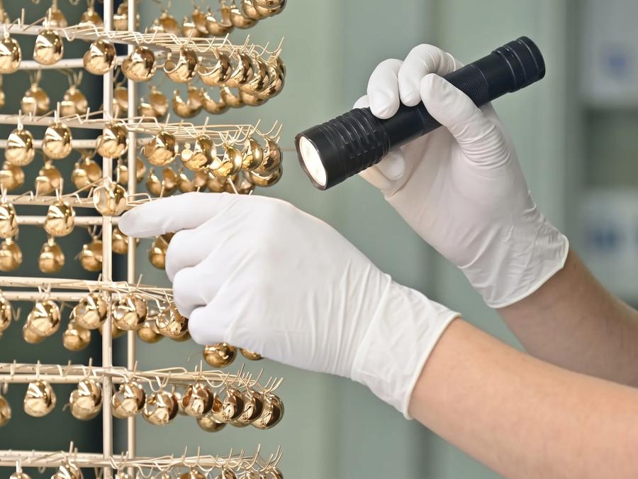 Quality inspector checking a batch of plated jewelry under inspection light