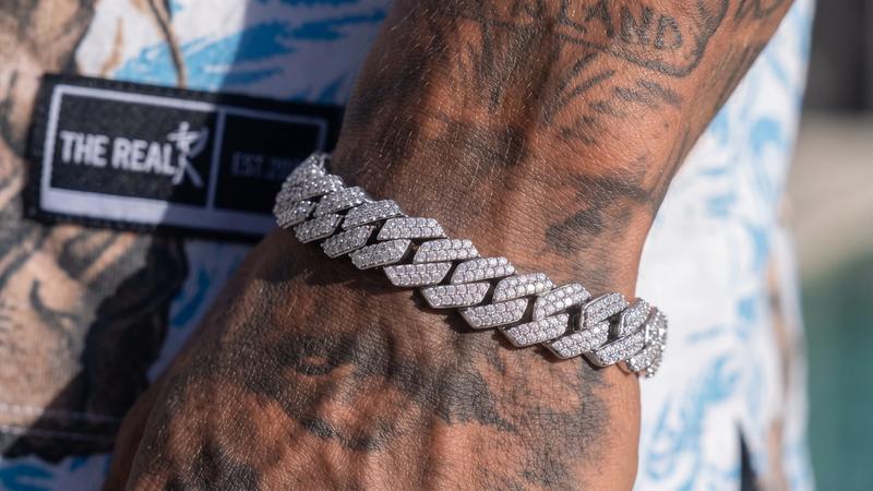 Silver Cuban link bracelet worn on a tattooed wrist