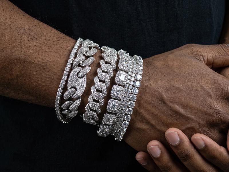 Stacked iced-out Cuban link and tennis bracelets worn on wrist