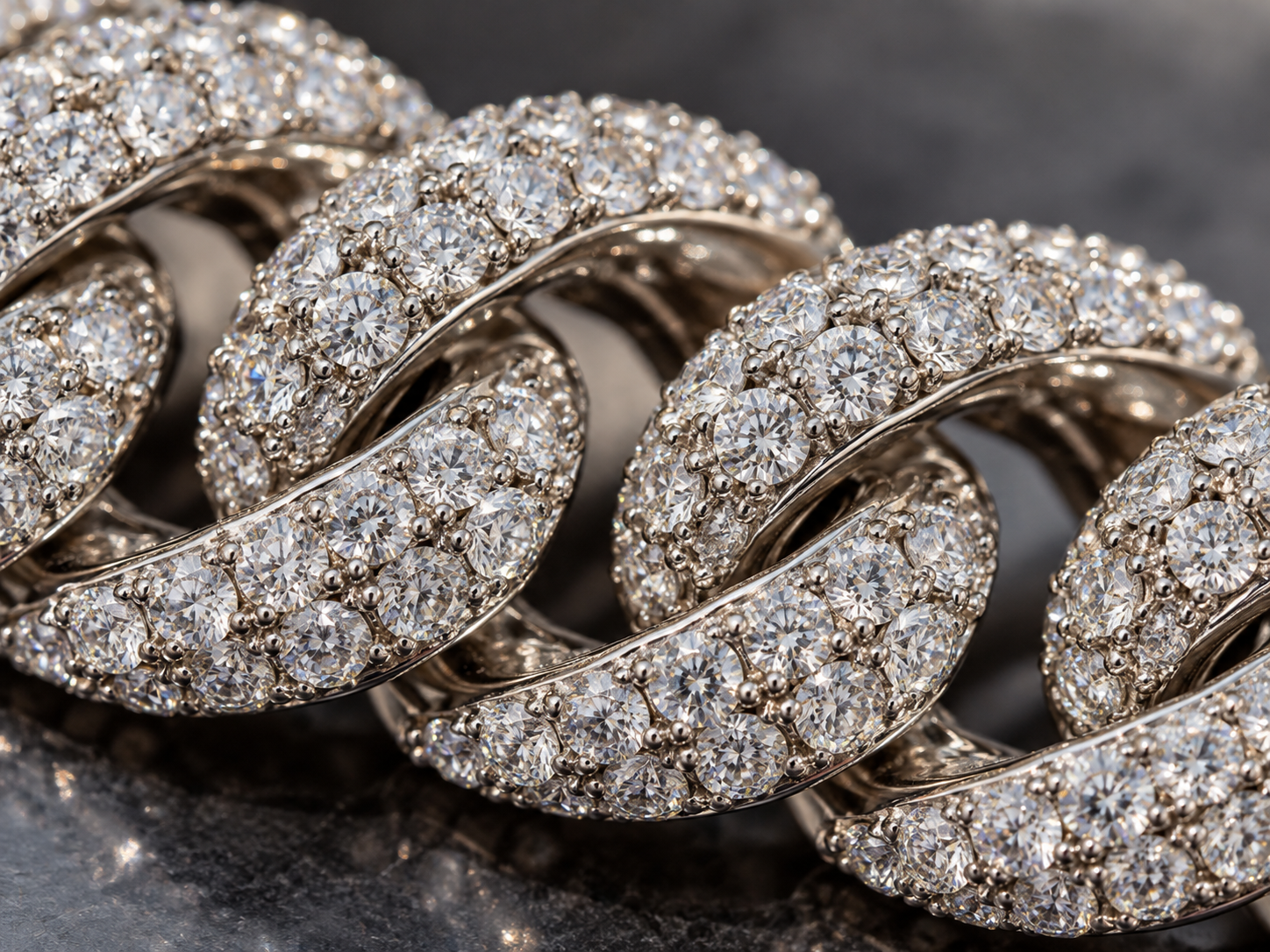 Close-up of an iced out Cuban chain showing delicate metal prongs securing the stones in place