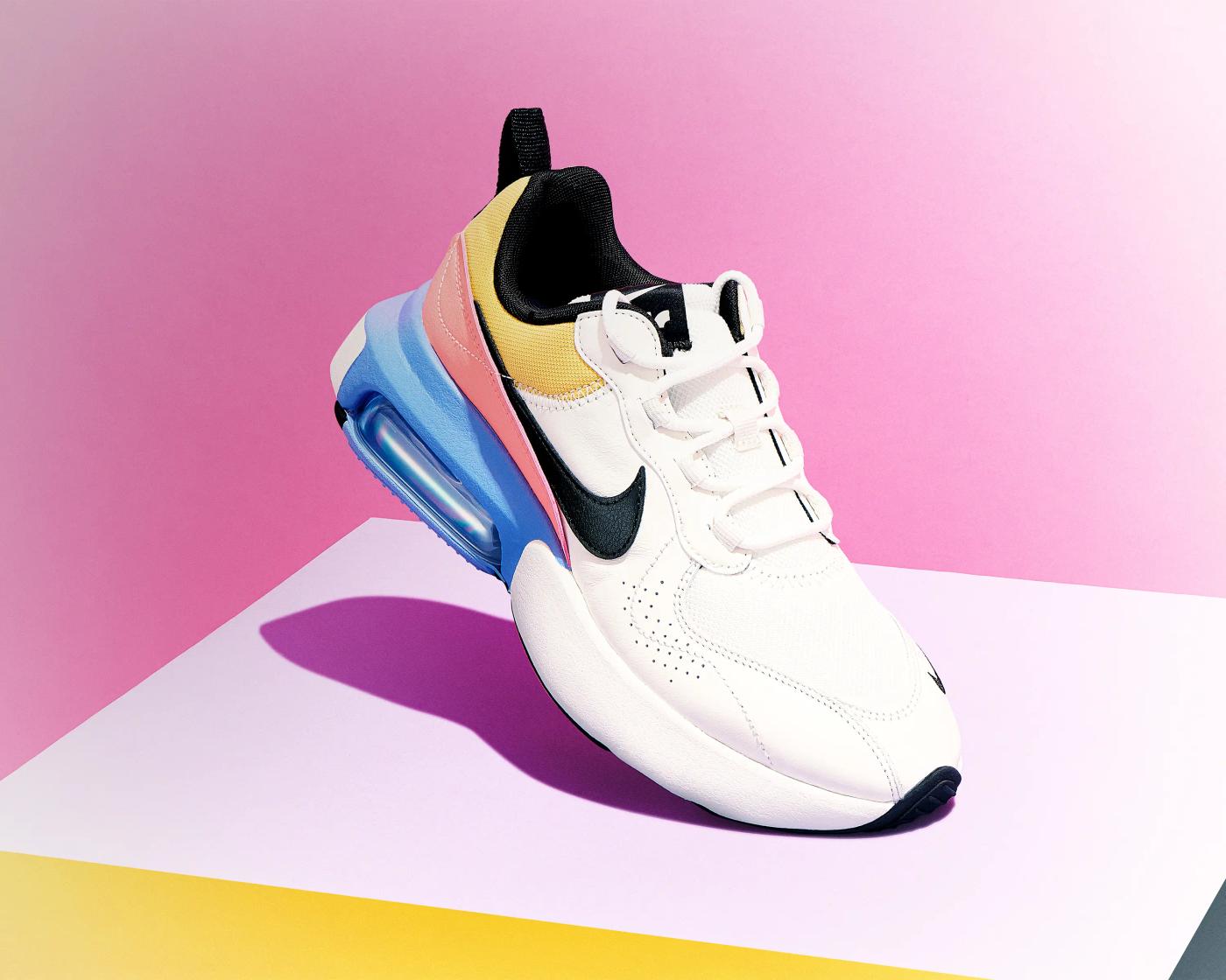 Nike trainer with multicolour sole on pastel geometric surface against pink gradient backdrop, editorial footwear photography London