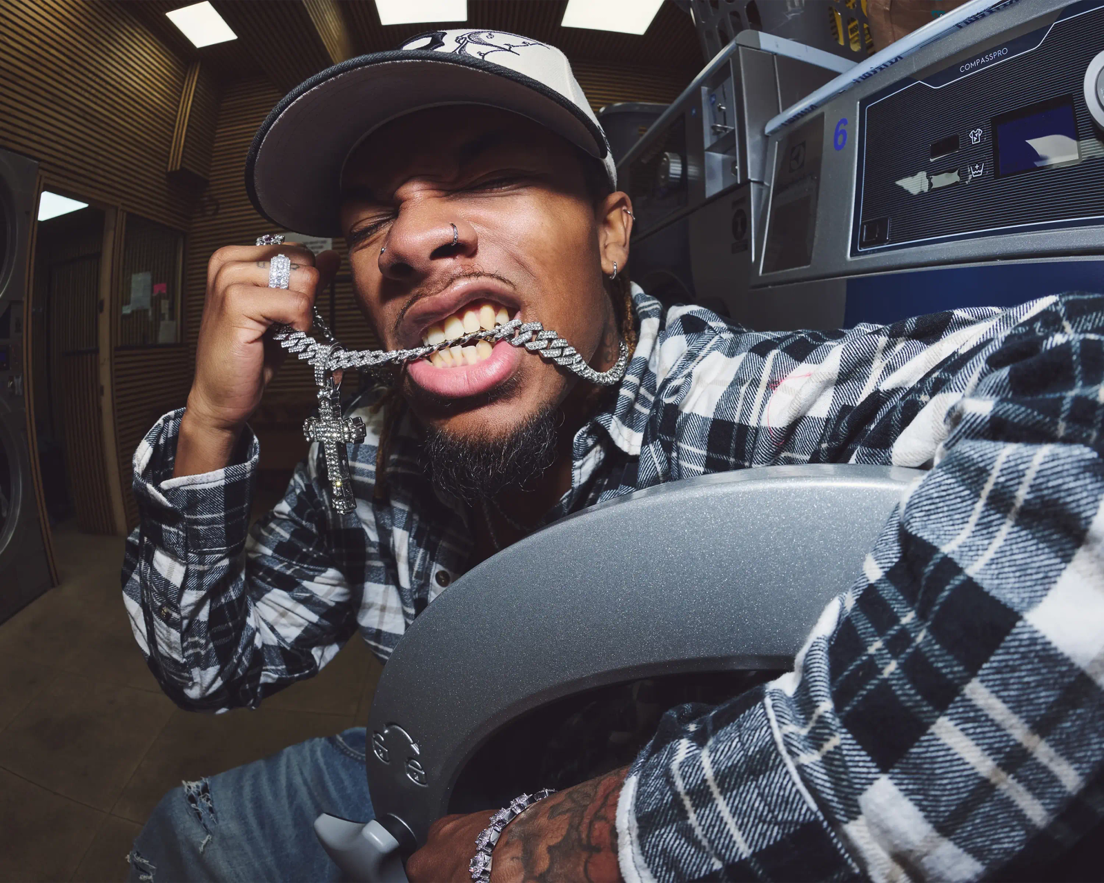 male model biting diamond Cuban link chain in launderette, close up editorial portrait, urban fashion photography South London