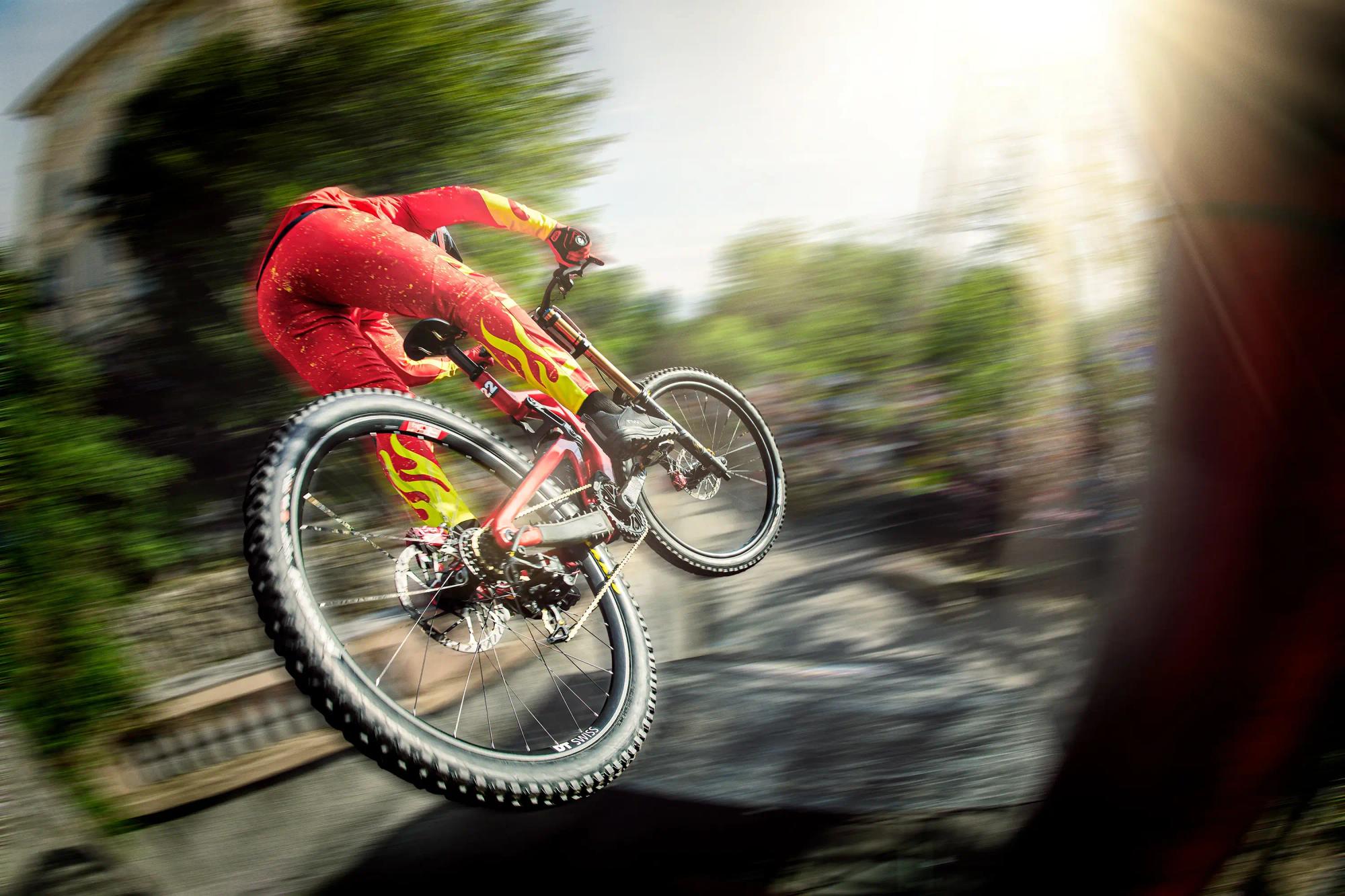 mountain biker mid air above city during urban downhill race, dramatic perspective, extreme sports photography