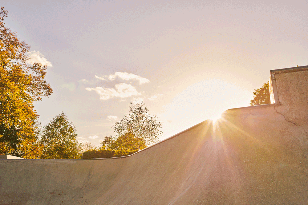 bmx rider standing on ramp at sunset holding bike, warm light, sports portrait photography