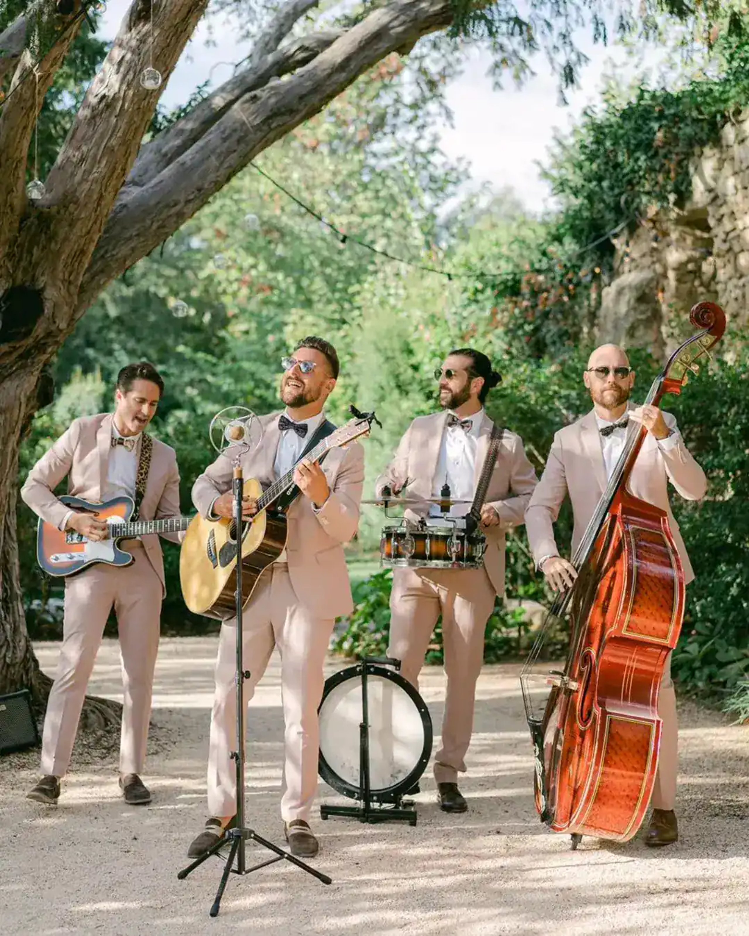 Four acoustic musicians playing together in a garden