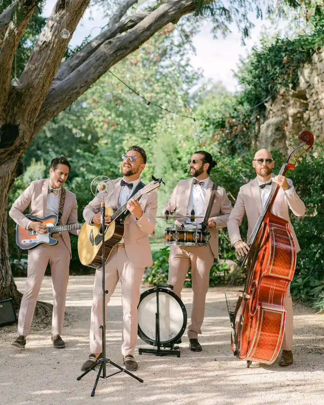 Four acoustic musicians playing together in a garden