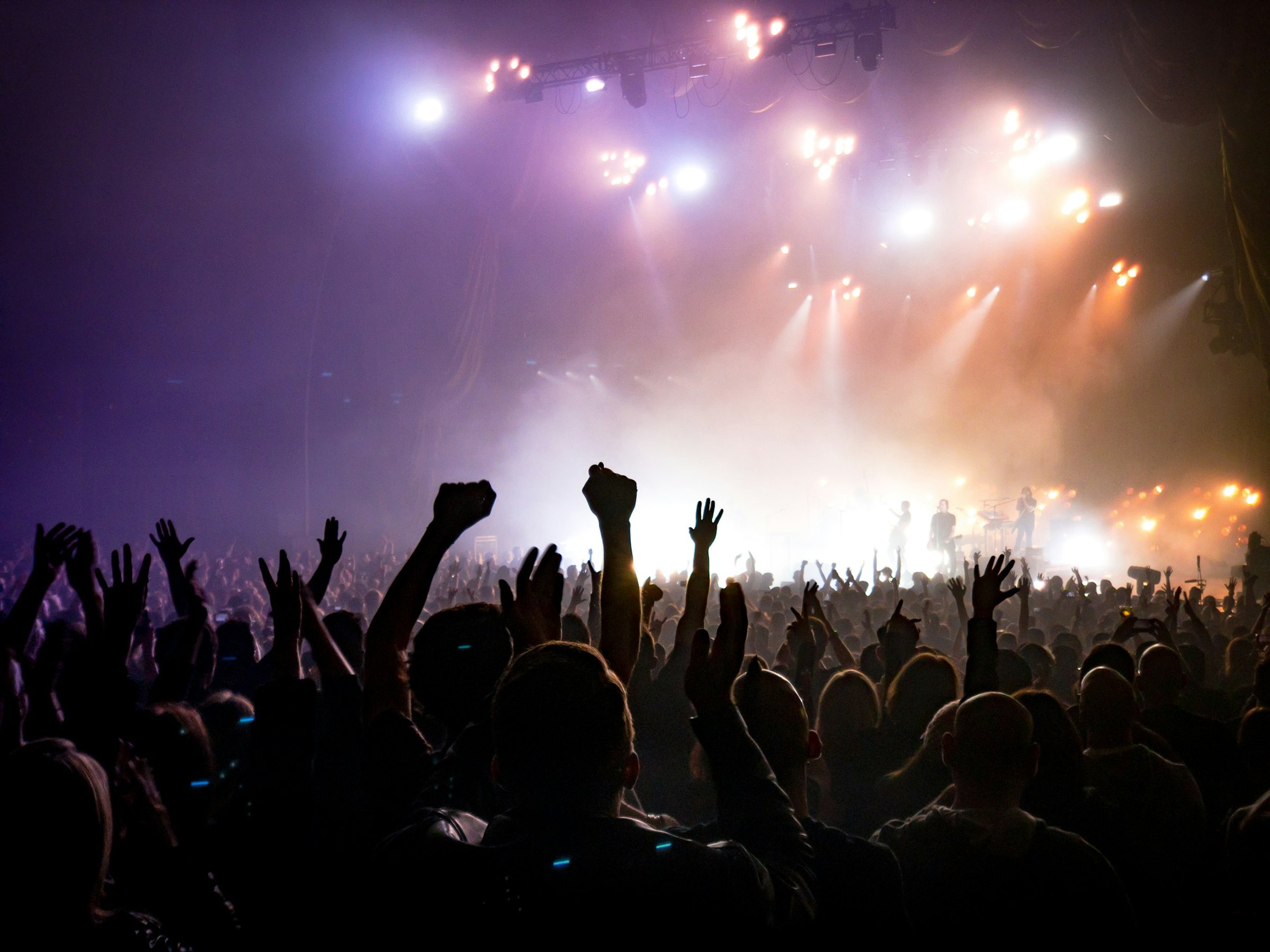 Beams of stage light sweeping over raised hands