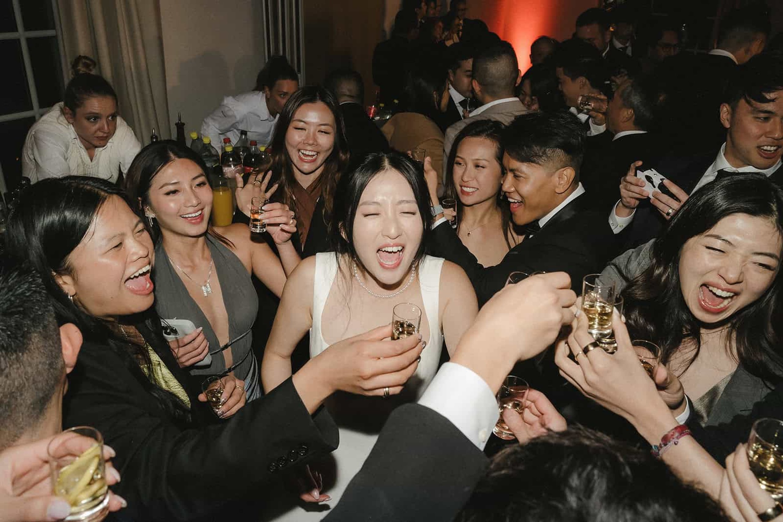Guests laughing and raising their glasses at an evening celebration