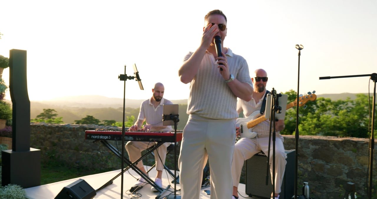 A saxophonist and keyboard player performing outdoors at sunset
