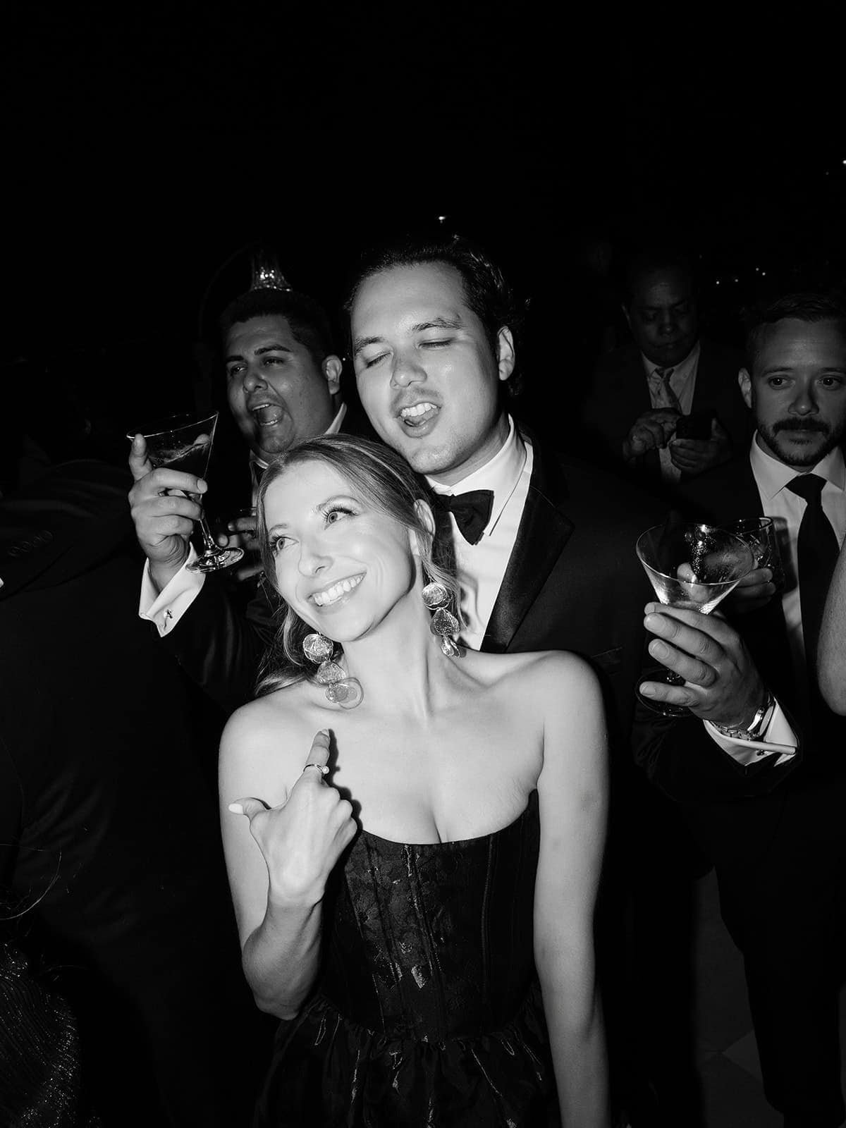 A couple raising their glasses at a wedding dinner, in black and white