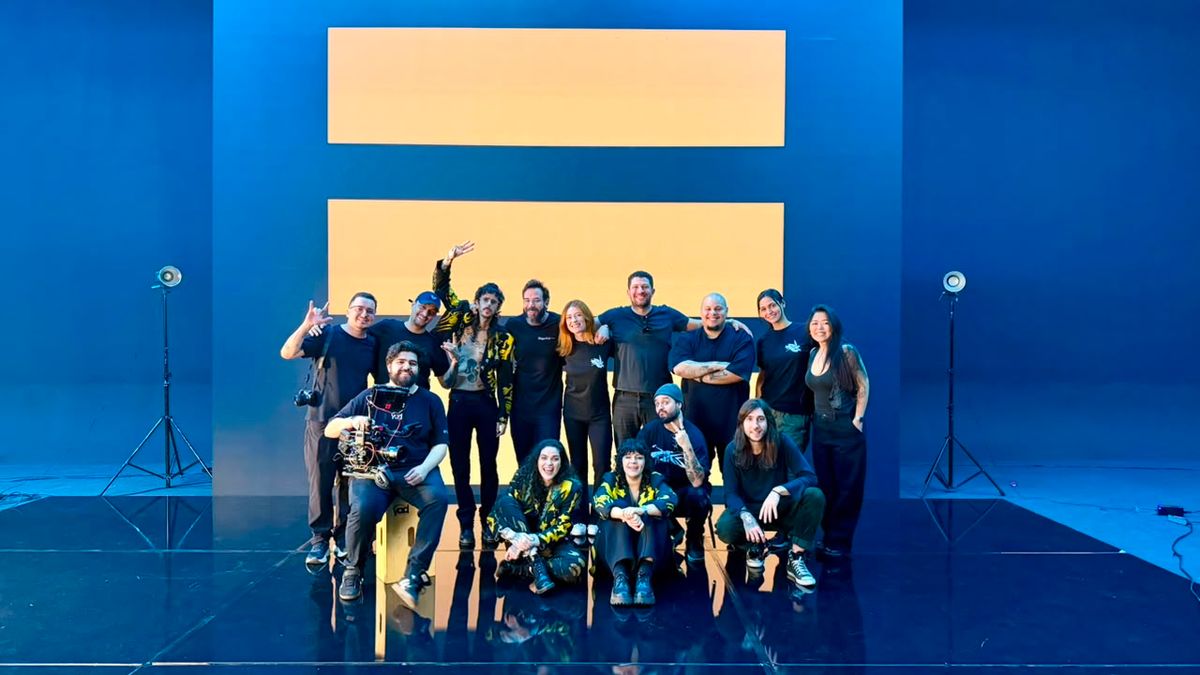 Equipe e banda posando juntas diante do painel de LED azul e laranja
