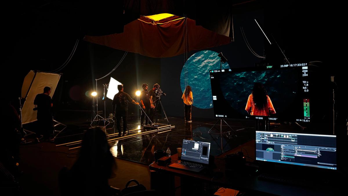 Set escuro com um círculo de mar no painel de LED, cantora diante dele e o monitor de referência mostrando o frame