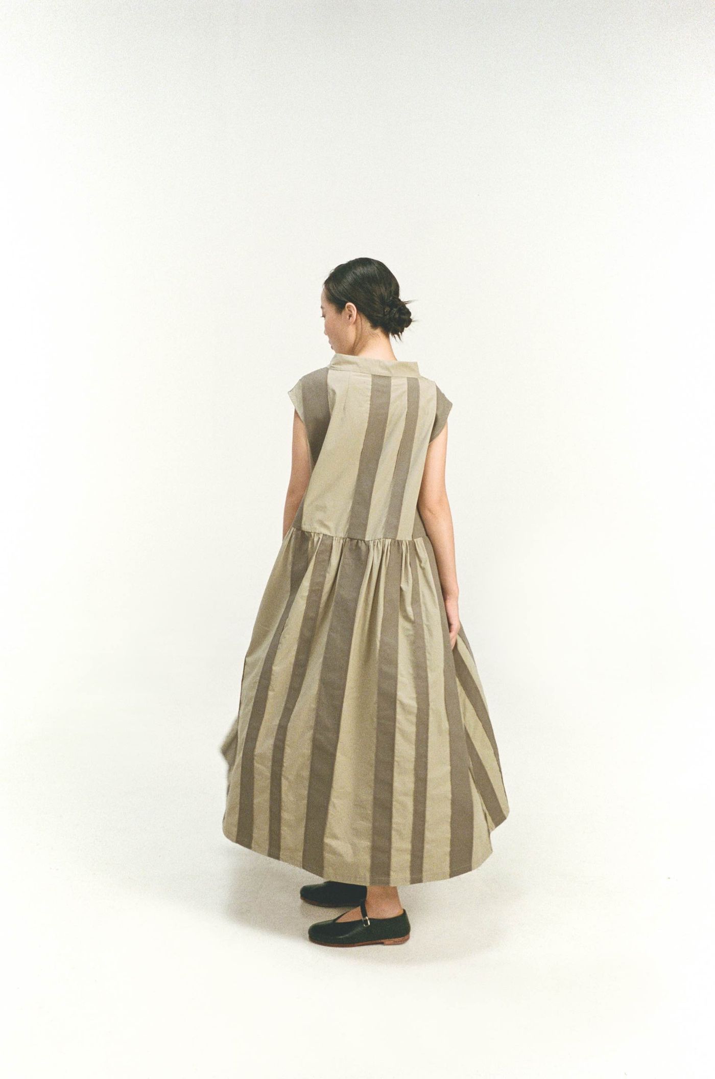 Model from behind in a striped beige sleeveless Unisecon dress
