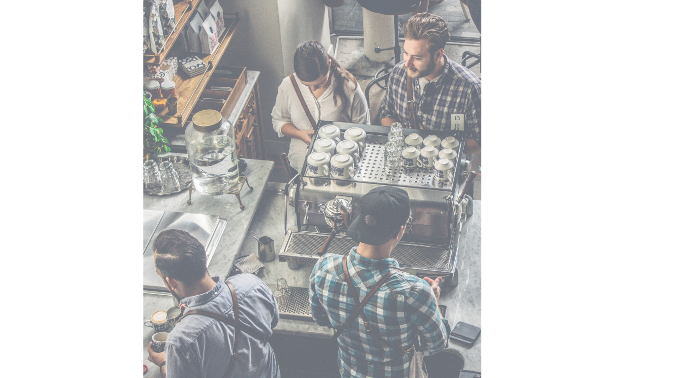 Photograph of small coffee store with employees working at barista