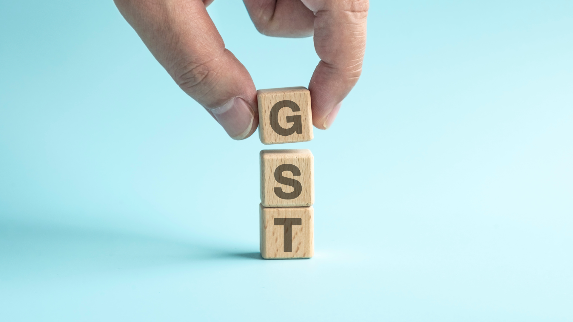 Person Building Blocks that spell GST (Goods and Services Tax)