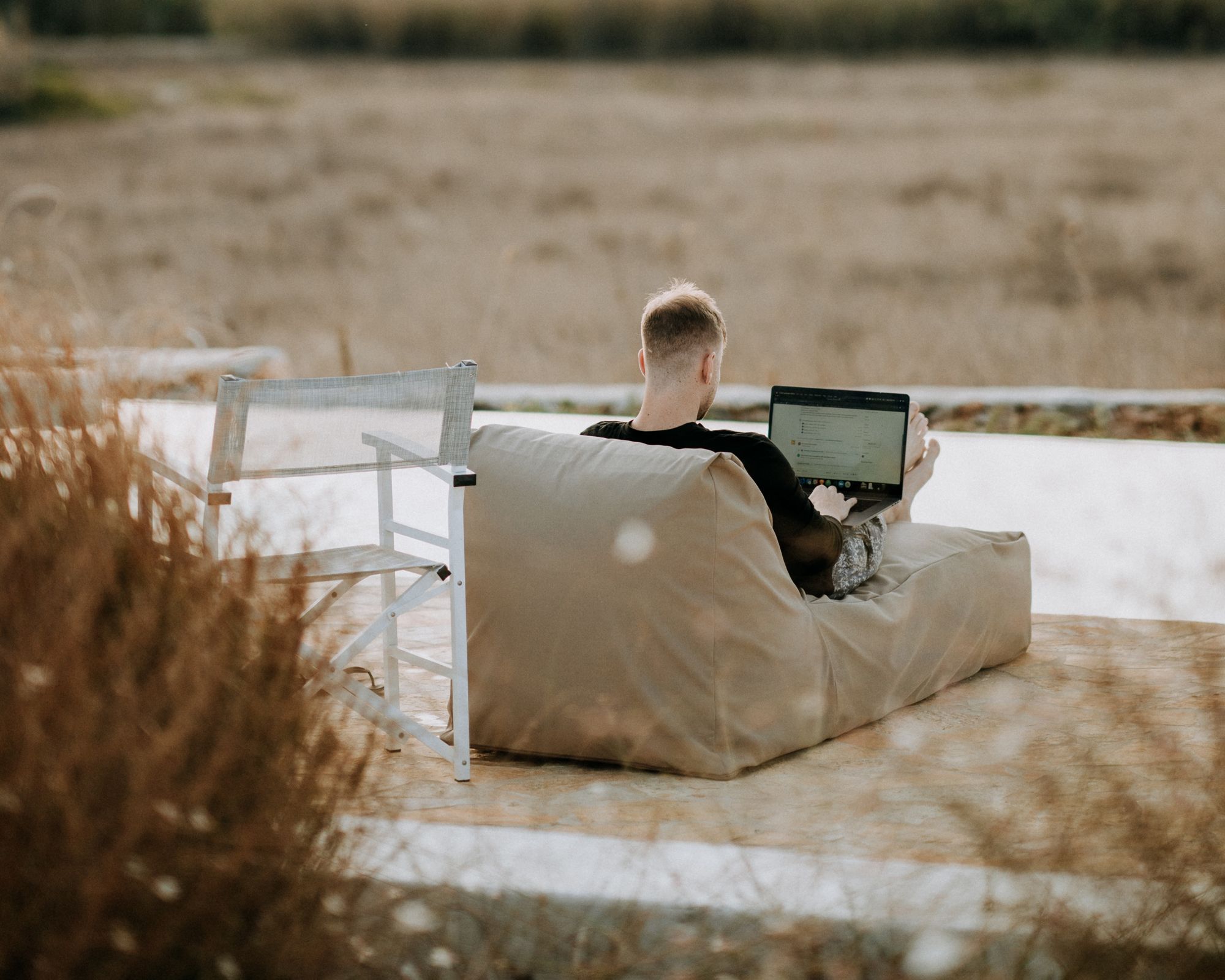 Man sitting by lake with a laptop