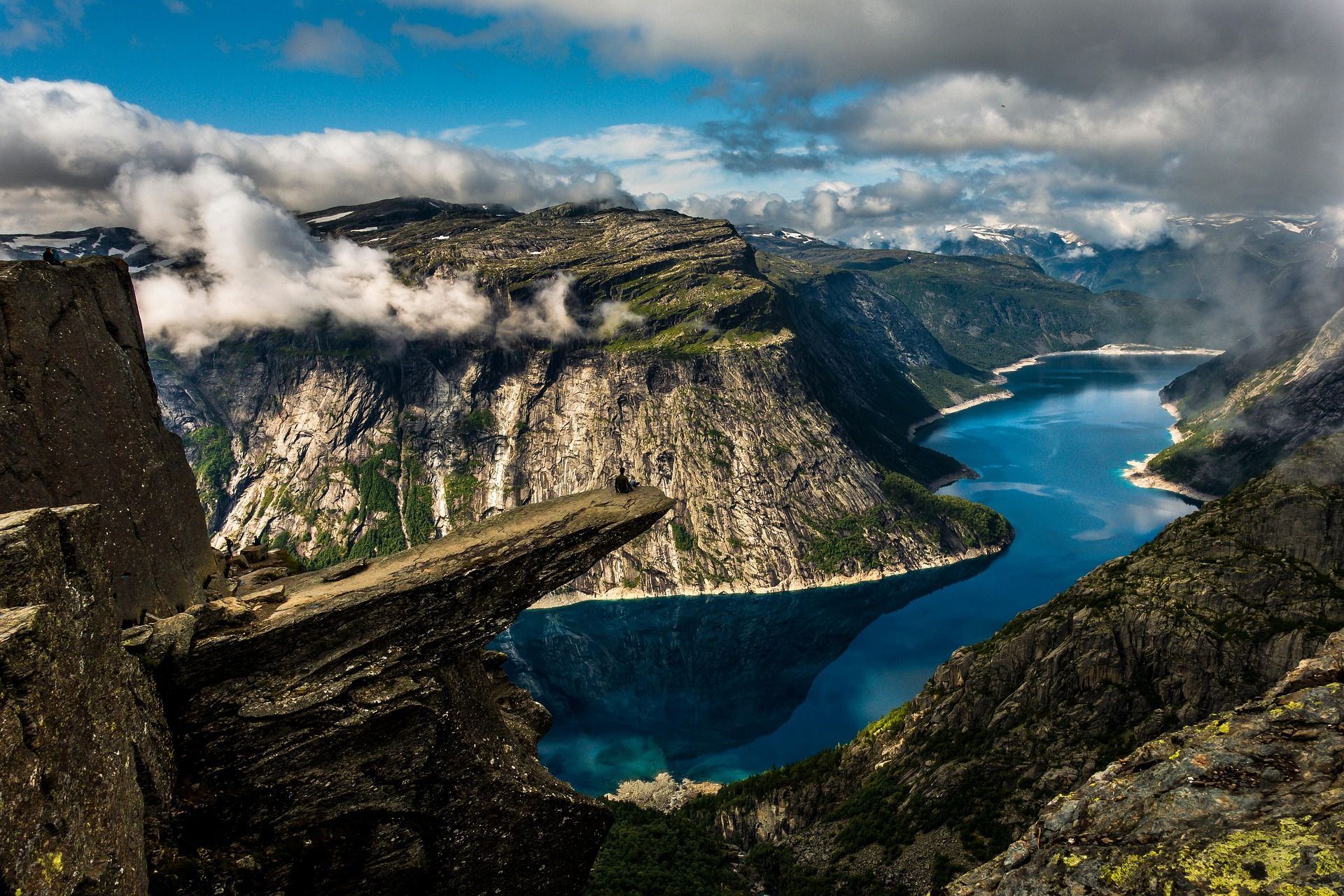 Bilde av trolltunga i Norge med vakre fjell og vann i bakgrunnen.