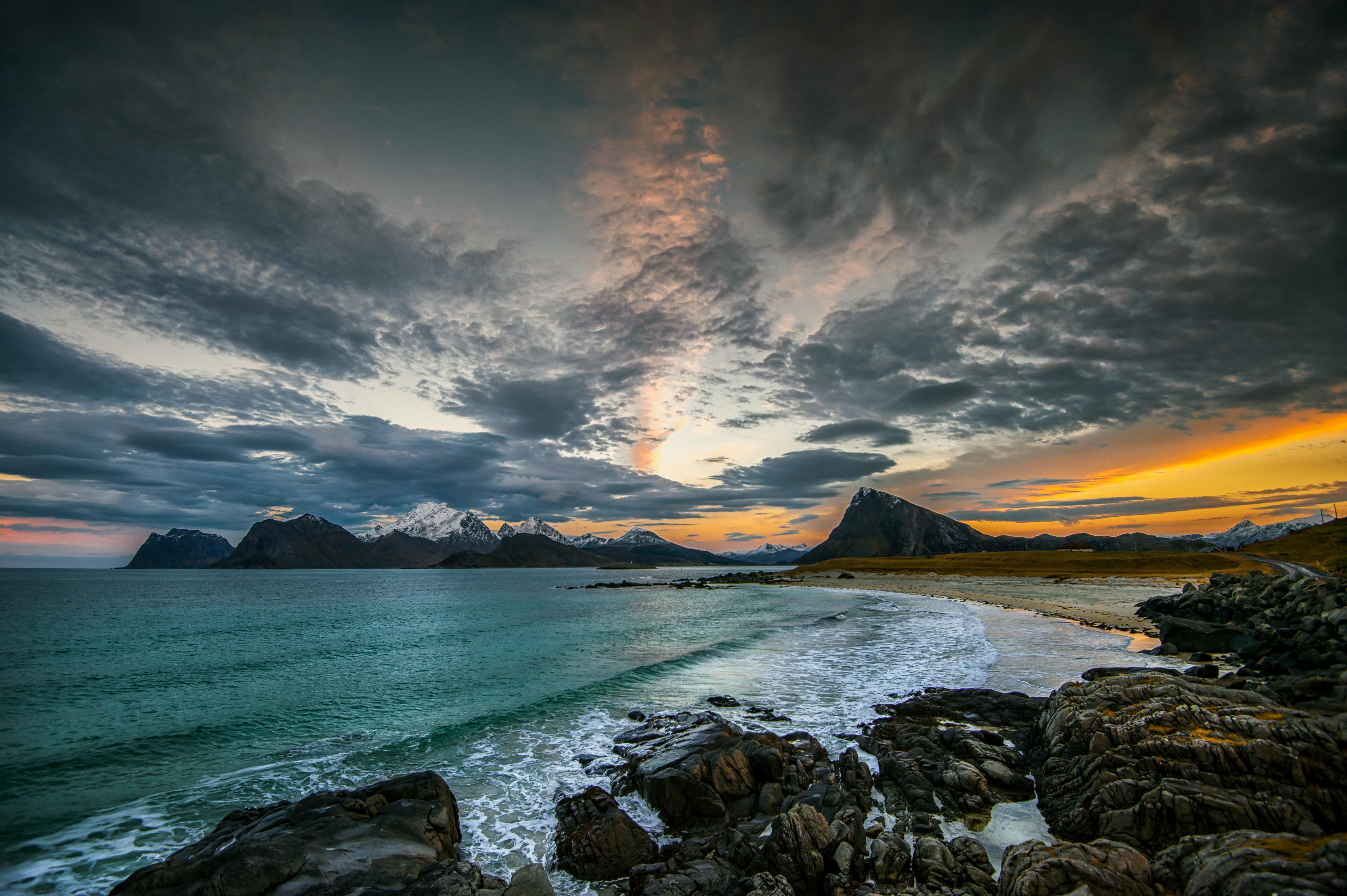 Bilde fra Lofoten i Norge med strand, fjell og sjø i bakgrunnen
