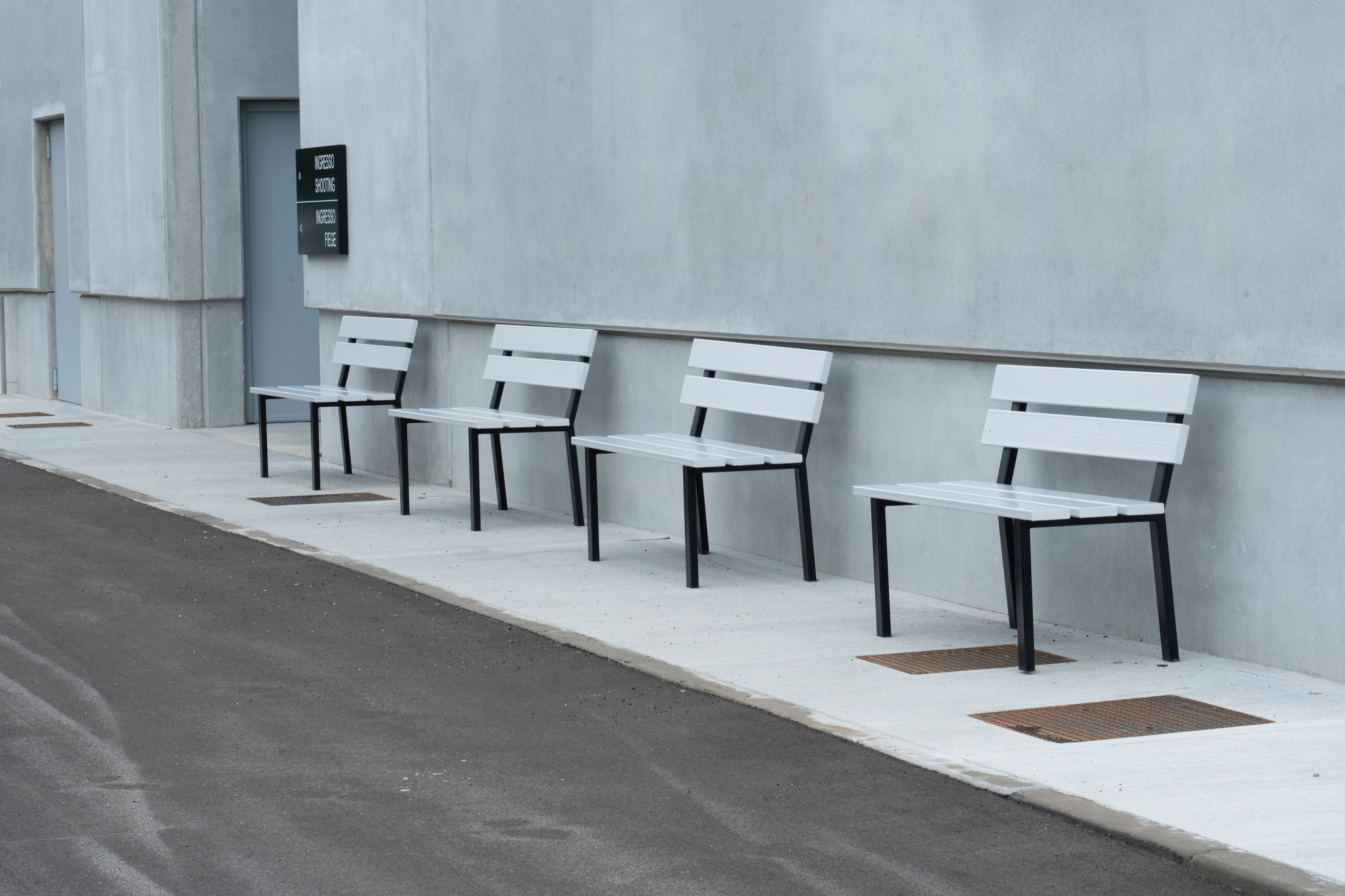 a row of white chairs are lined up on the sidewalk in front of a building .