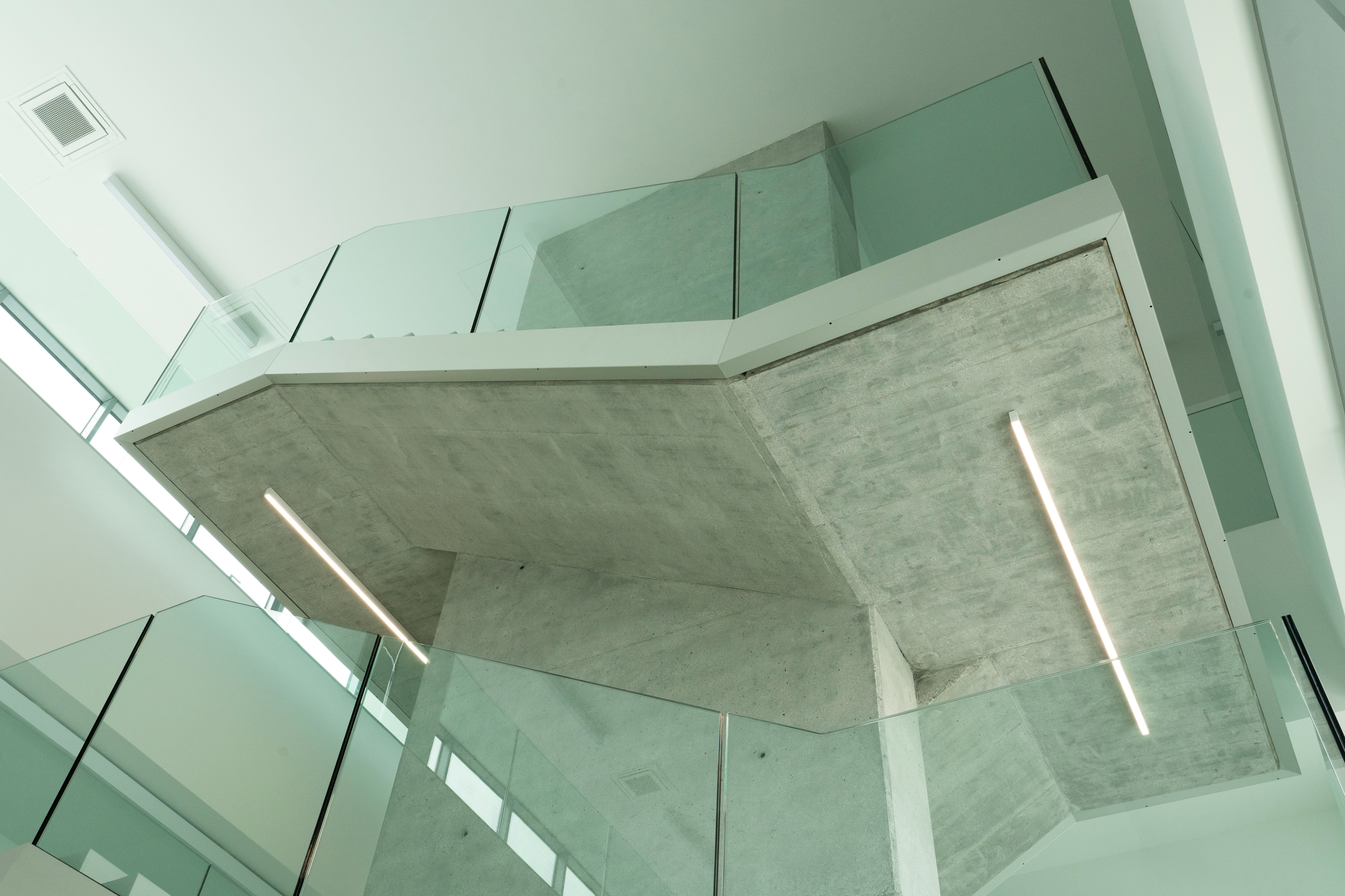 a staircase with a glass railing and a concrete ceiling in a building .