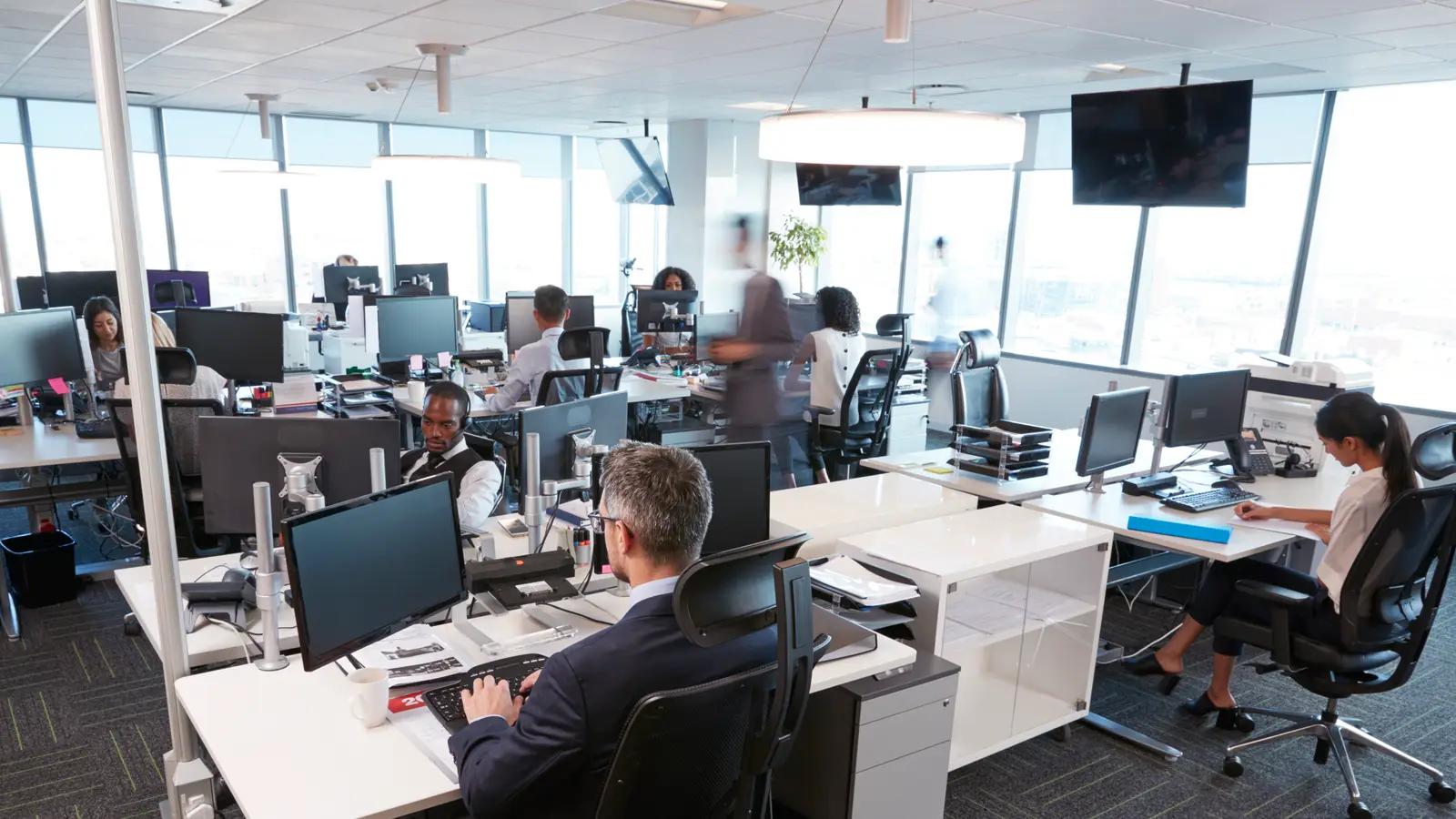 A busy open-plan office with staff at their workstations