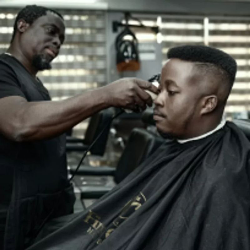 Barber strzyże klienta maszynką w salonie
