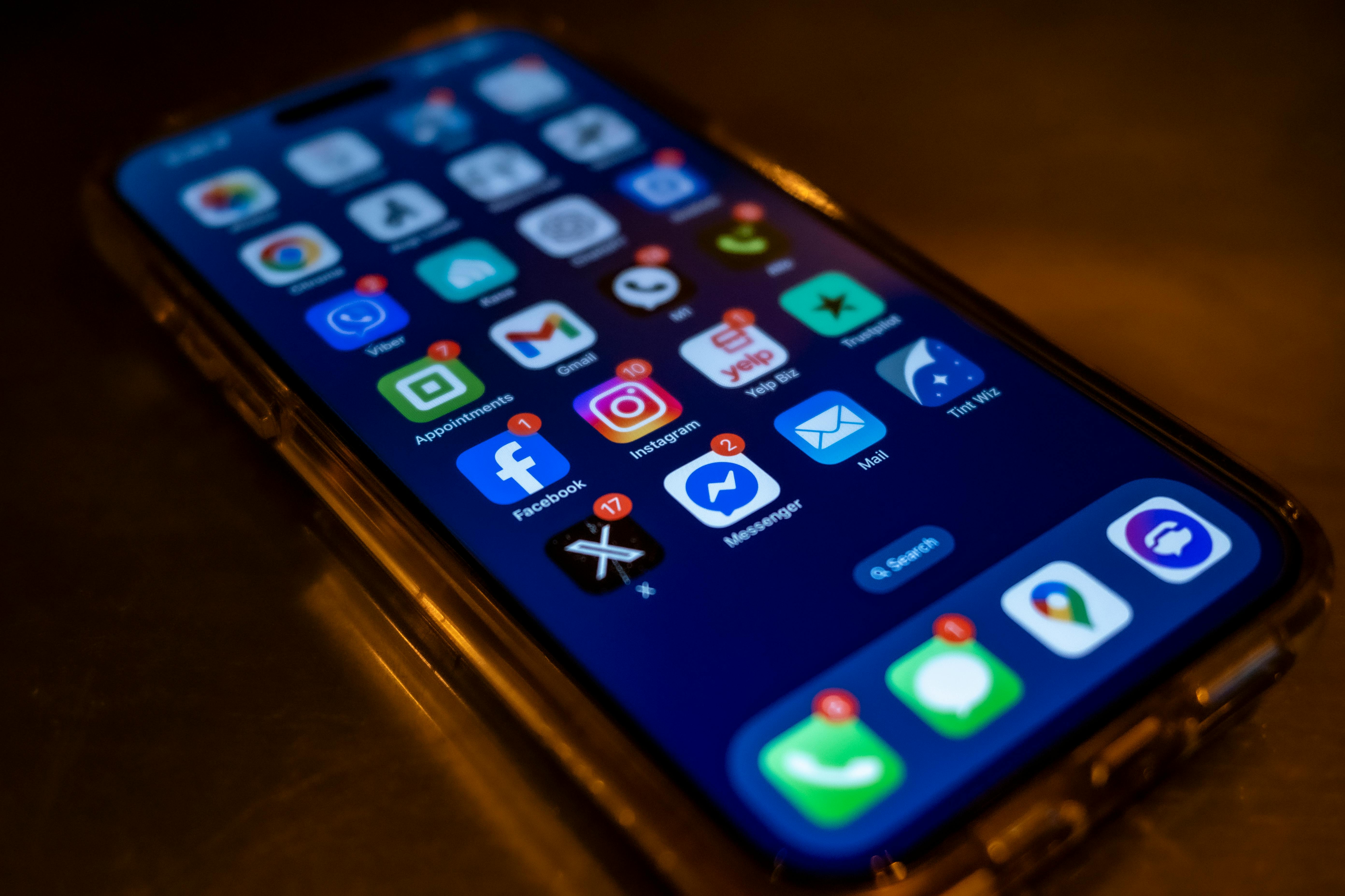   A smartphone home screen crowded with messaging and social apps showing unread notification badges, illustrating the sprawl of disconnected communication channels a wrestling program juggles.
