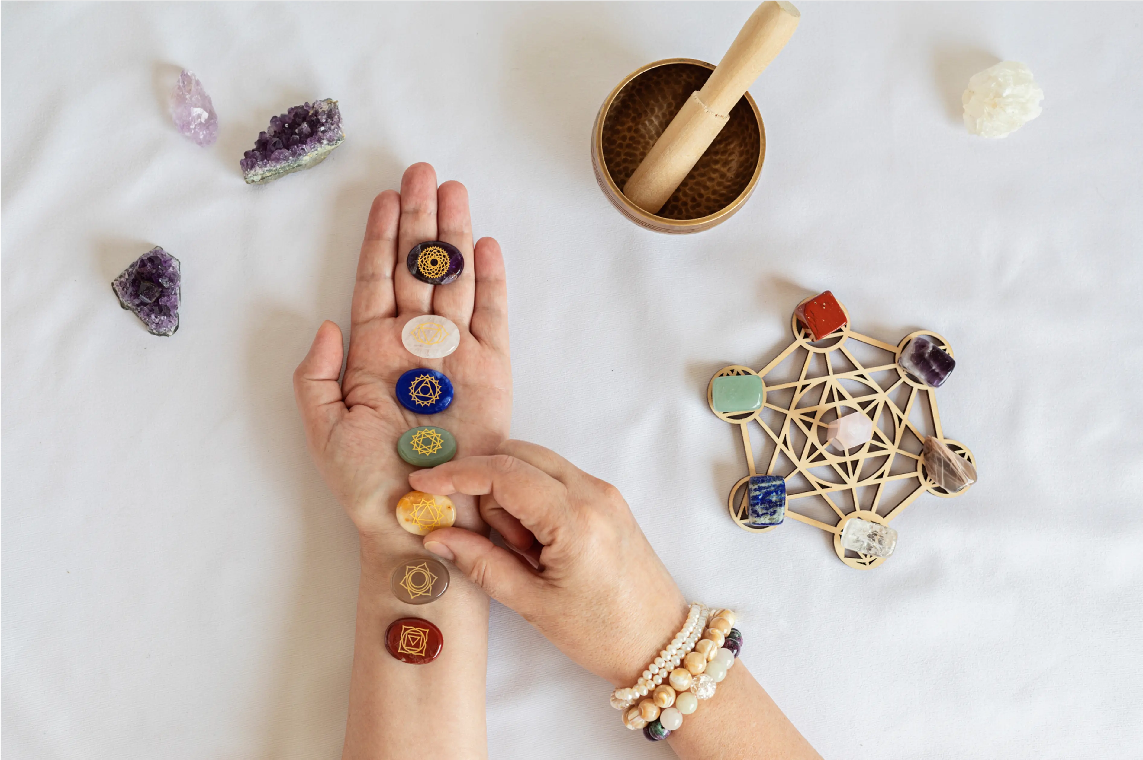 Range of charkra crystals in someones hand and a singing bowl