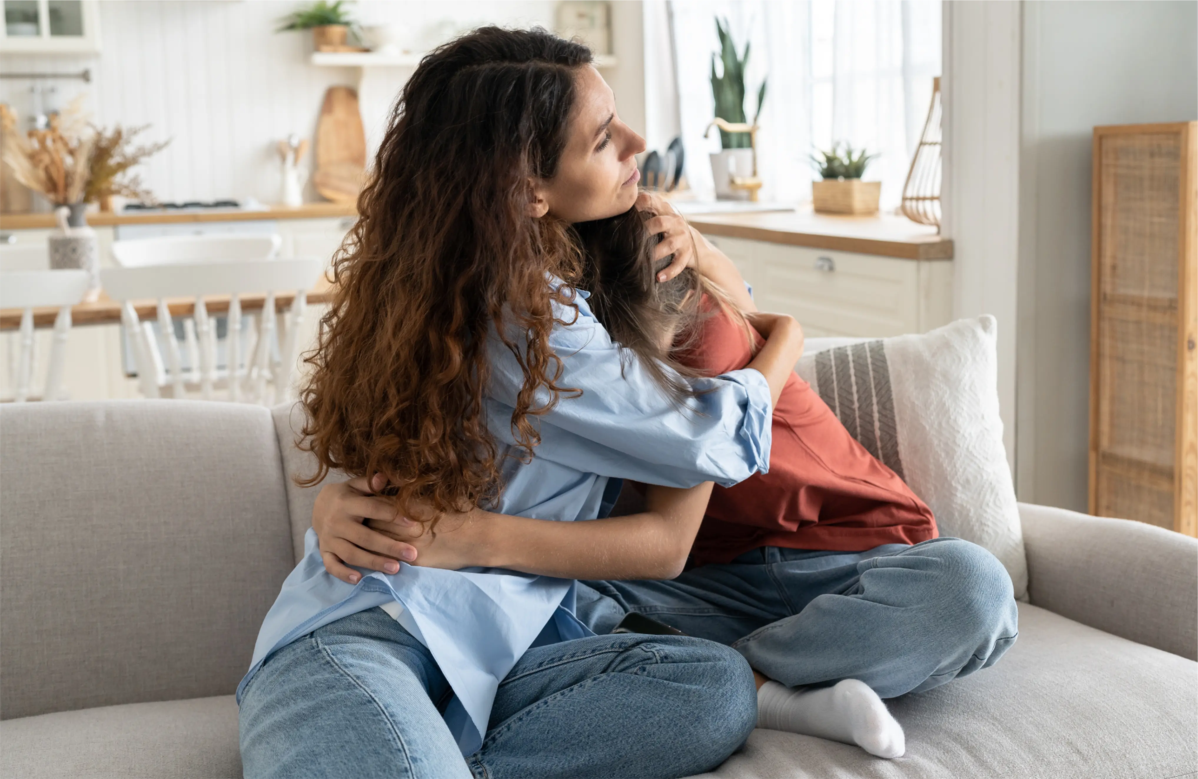 Mum hugging her teen on the sofa in support of her